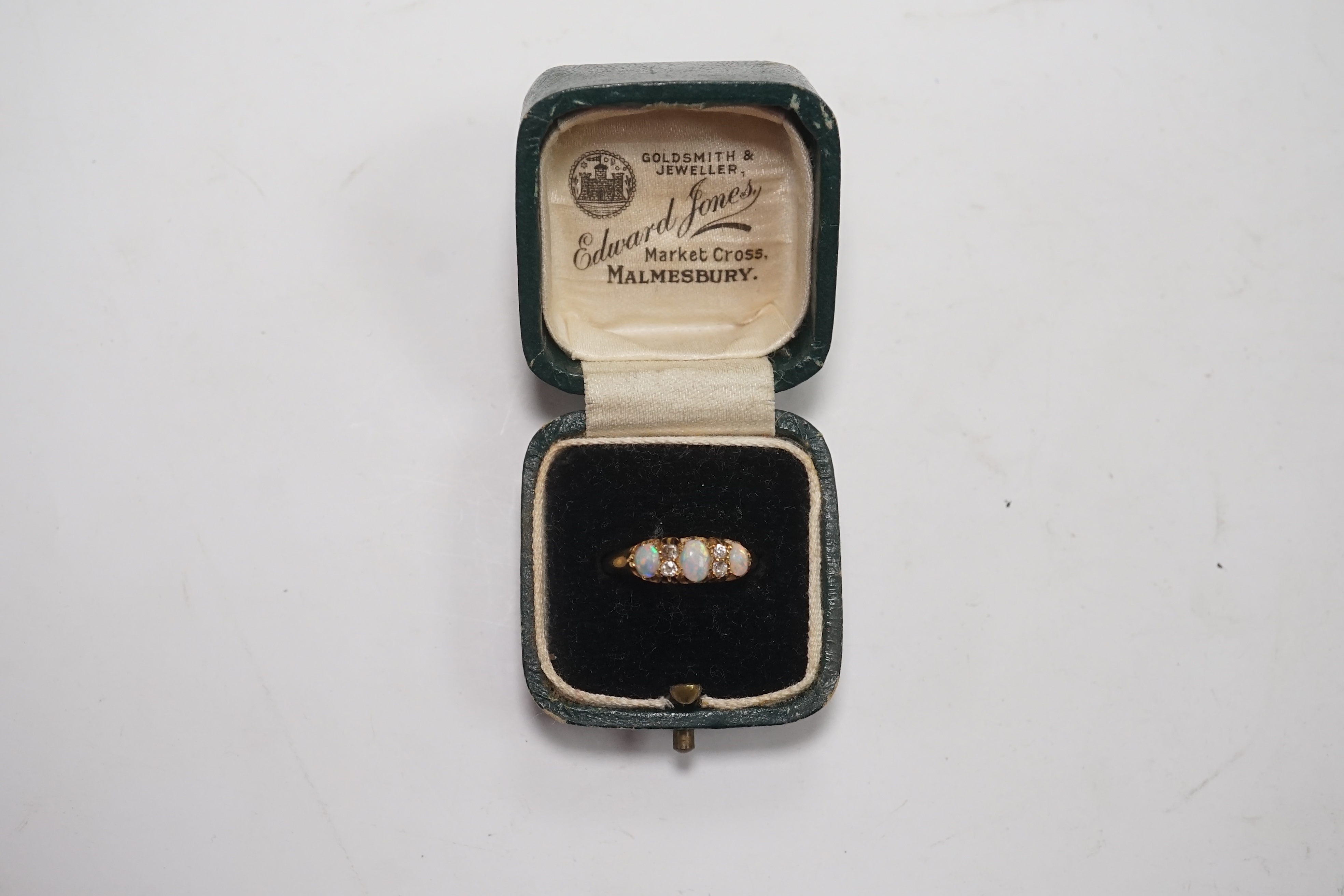 An early 20th century yellow metal and three stone white opal ring, with four stone diamond chip spacers, size M/N, gross weight 3 grams. Condition - poor to fair